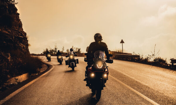 Group of Motorbikers Riding on Motorcycles along Mountainous Road in Mild Sunset Light. Extreme Sport. Active Life.